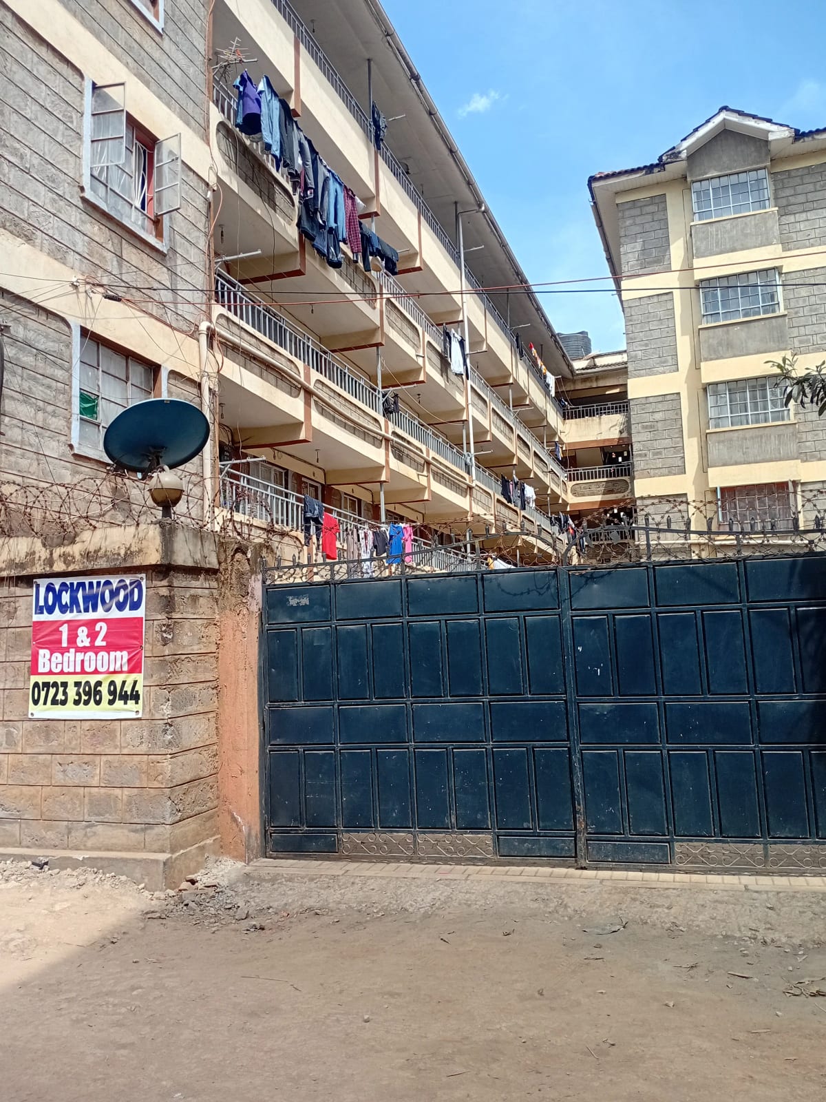 Multi-story residential building facade with blue metal gate entrance
