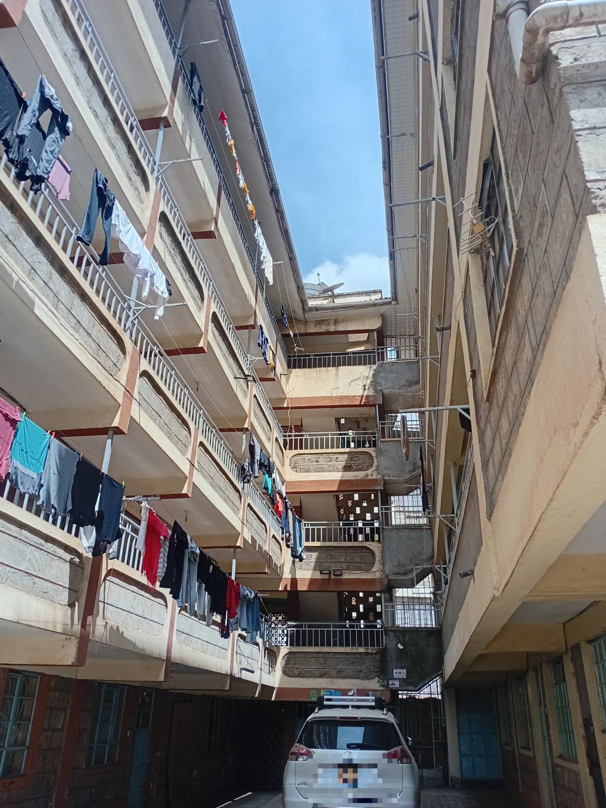 Multi-story residential building courtyard with parked vehicle