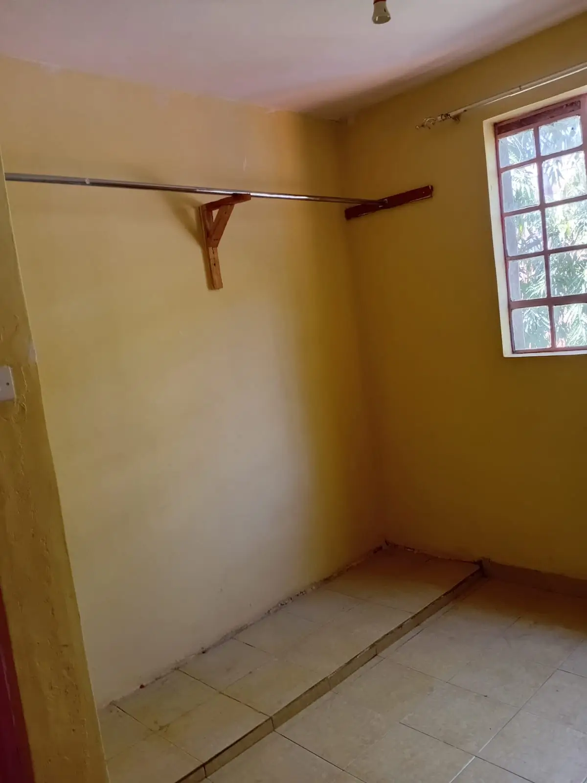 Empty bedroom with wooden rod and barred window