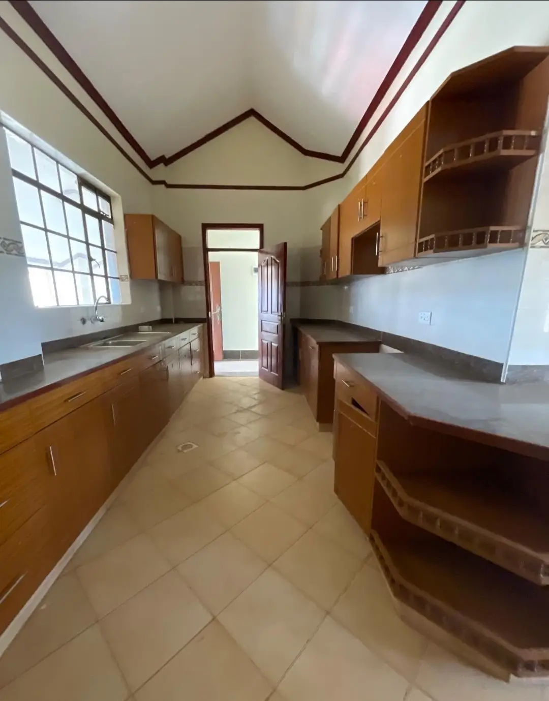 Galley kitchen with wooden cabinets, countertops, and storage shelving