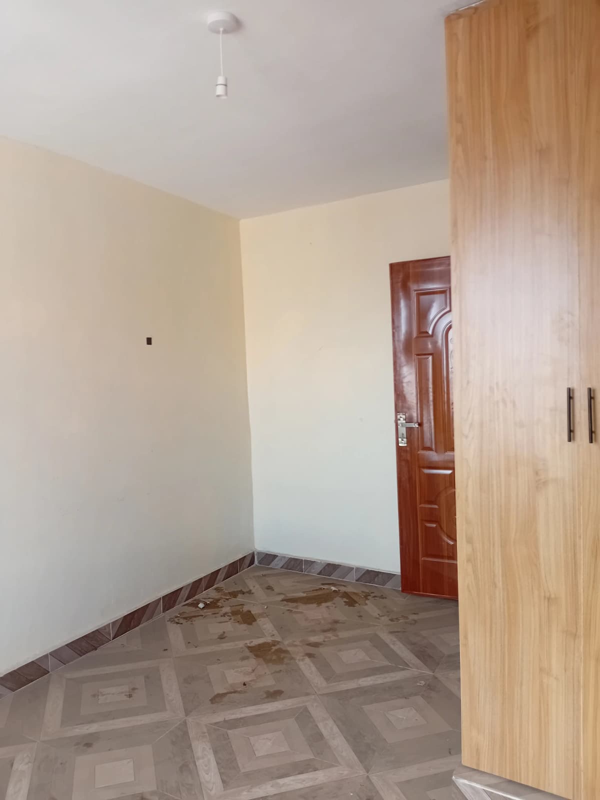 Empty bedroom with wooden wardrobe and geometric floor tiles