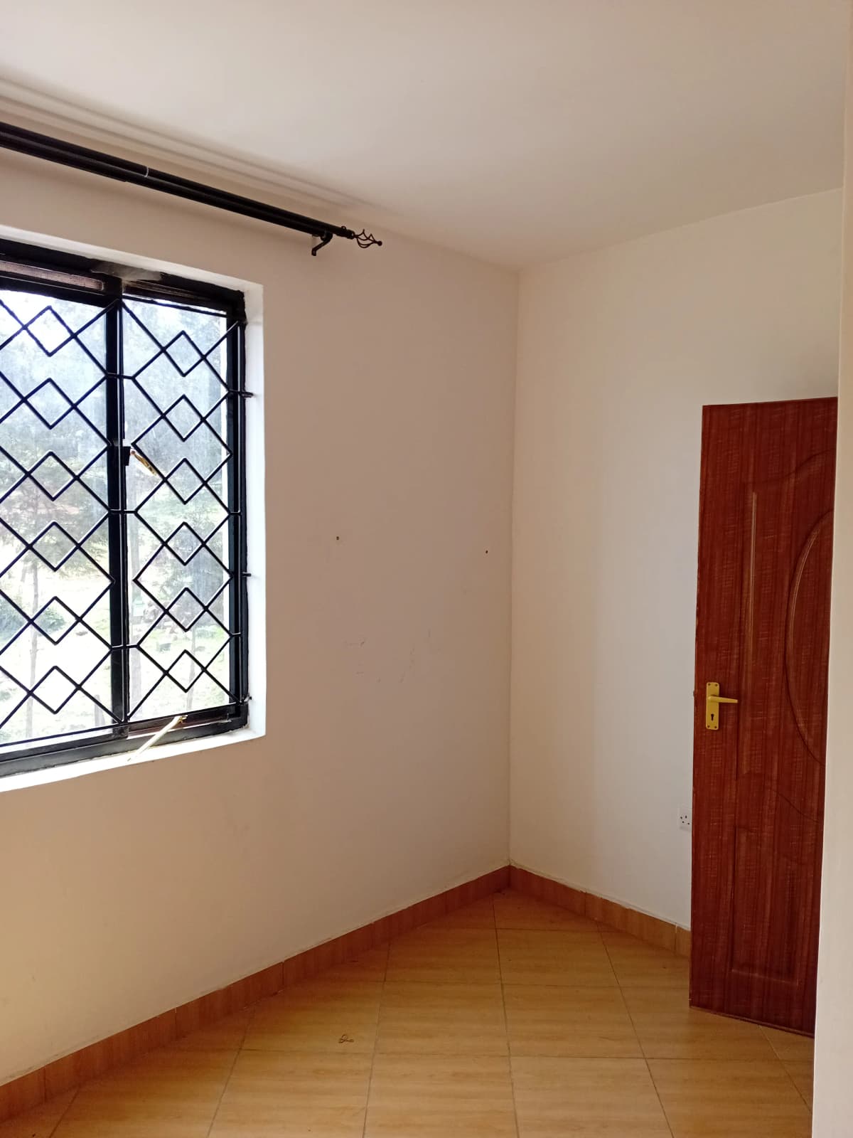 Empty bedroom with wooden floor and barred window