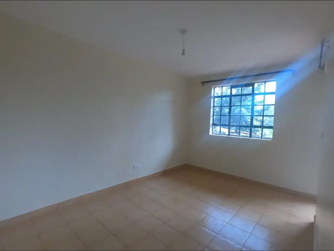 Bright empty bedroom with large window and tiled flooring
