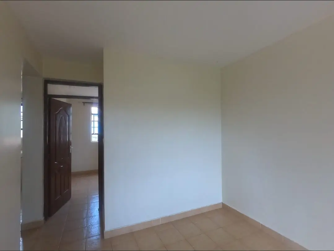 Empty bedroom with wooden door and pale walls