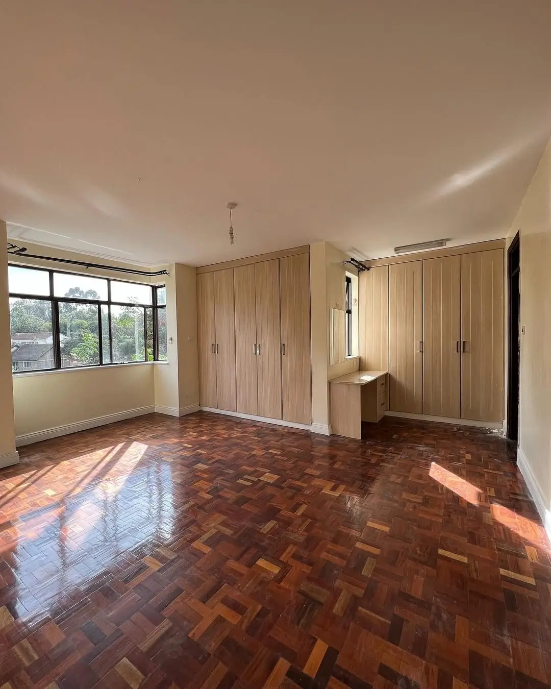 Spacious master bedroom with herringbone wood flooring and built-in wardrobes