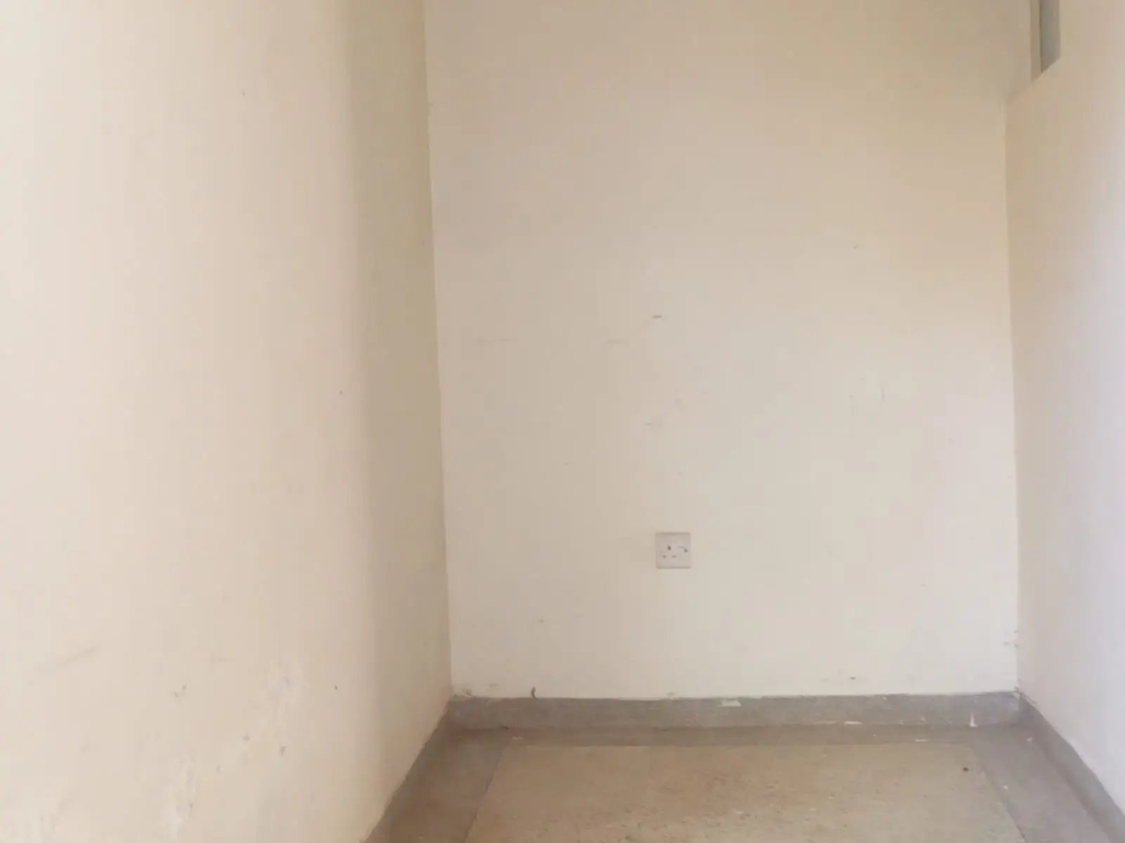Empty bedroom with bare concrete floor and cream walls