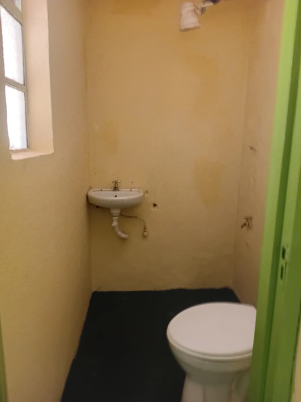 Compact bathroom with toilet, pedestal sink, and window