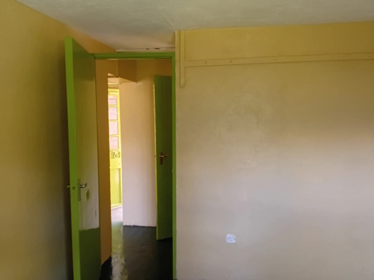 Narrow hallway with green-framed doorways and yellow walls
