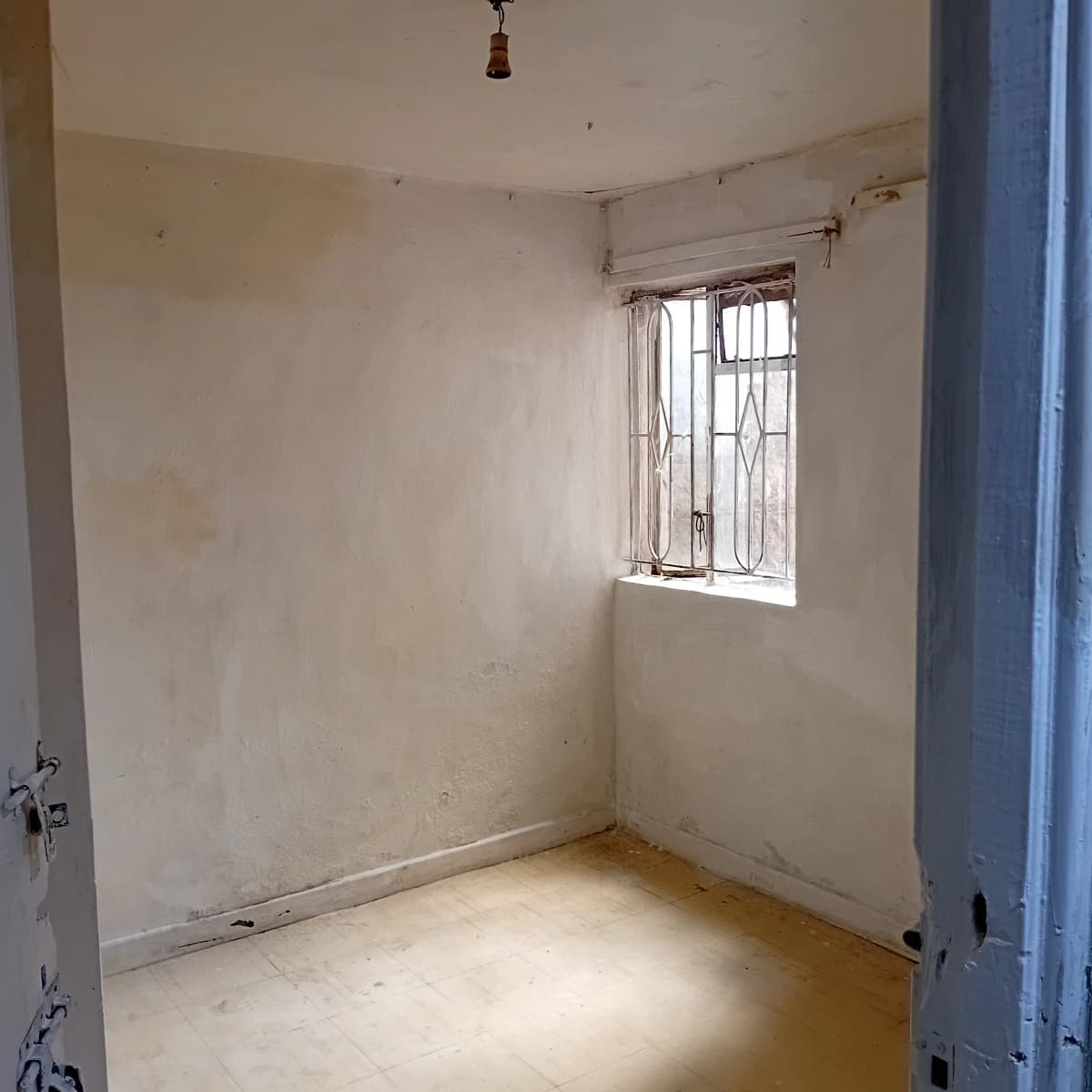 Unfurnished bedroom with window and plain walls