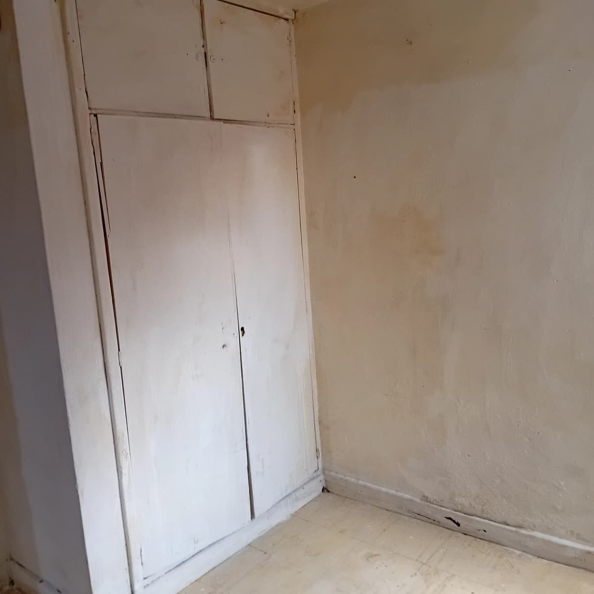 Empty bedroom with built-in wardrobe and bare walls