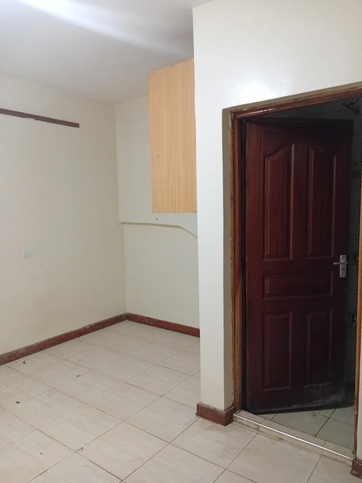 Empty room with tiled floor and wooden door entrance