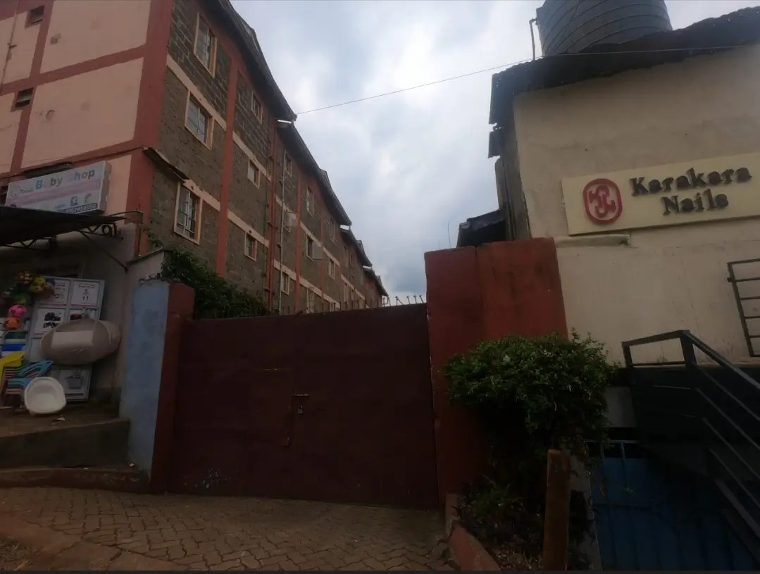 Compound entrance with red gate and residential buildings