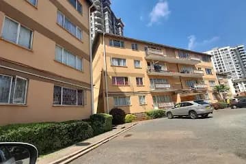 Multi-story residential building facade with parking area