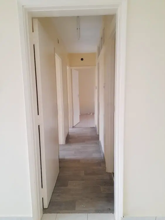 Long hallway with wooden flooring and white walls