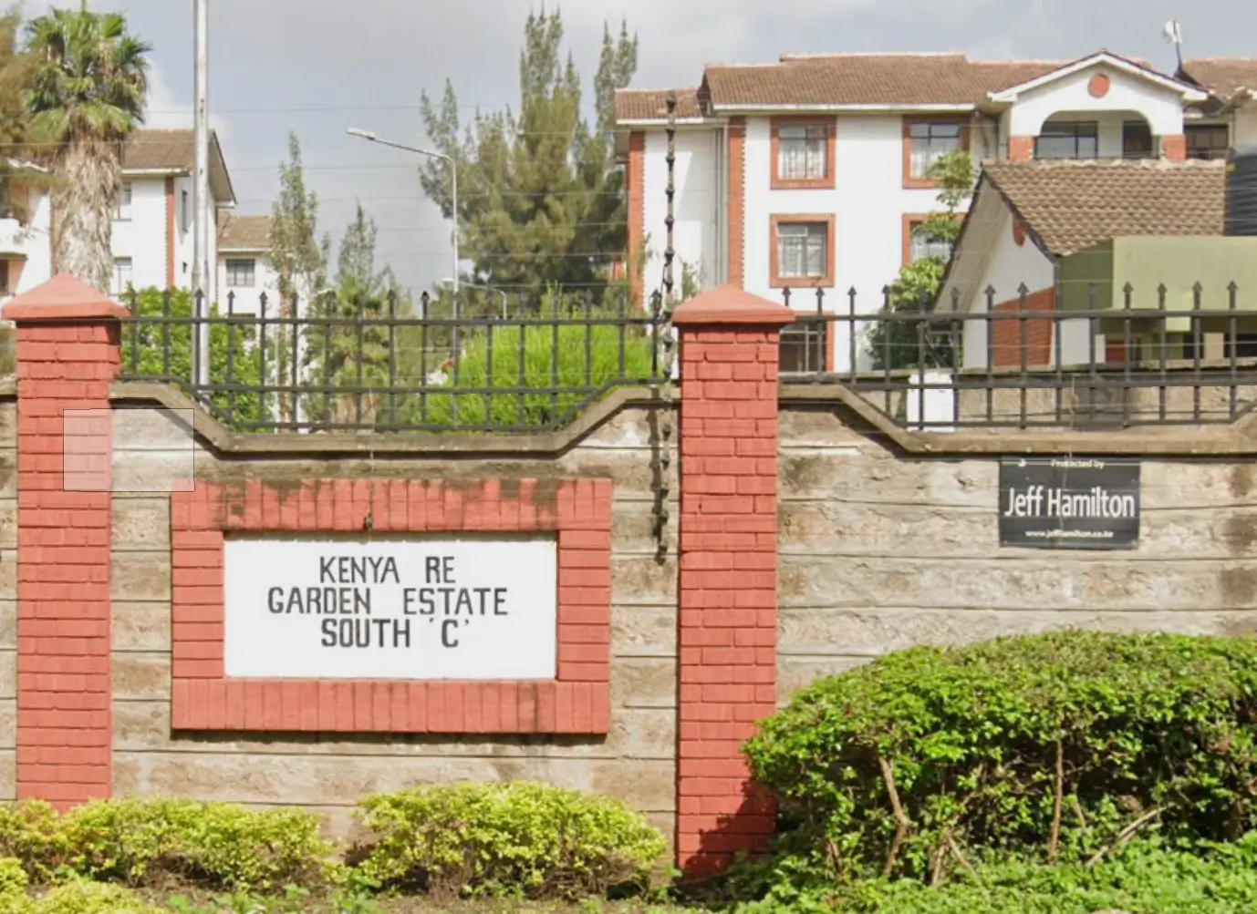 Gated estate entrance with brick pillars and green landscaping