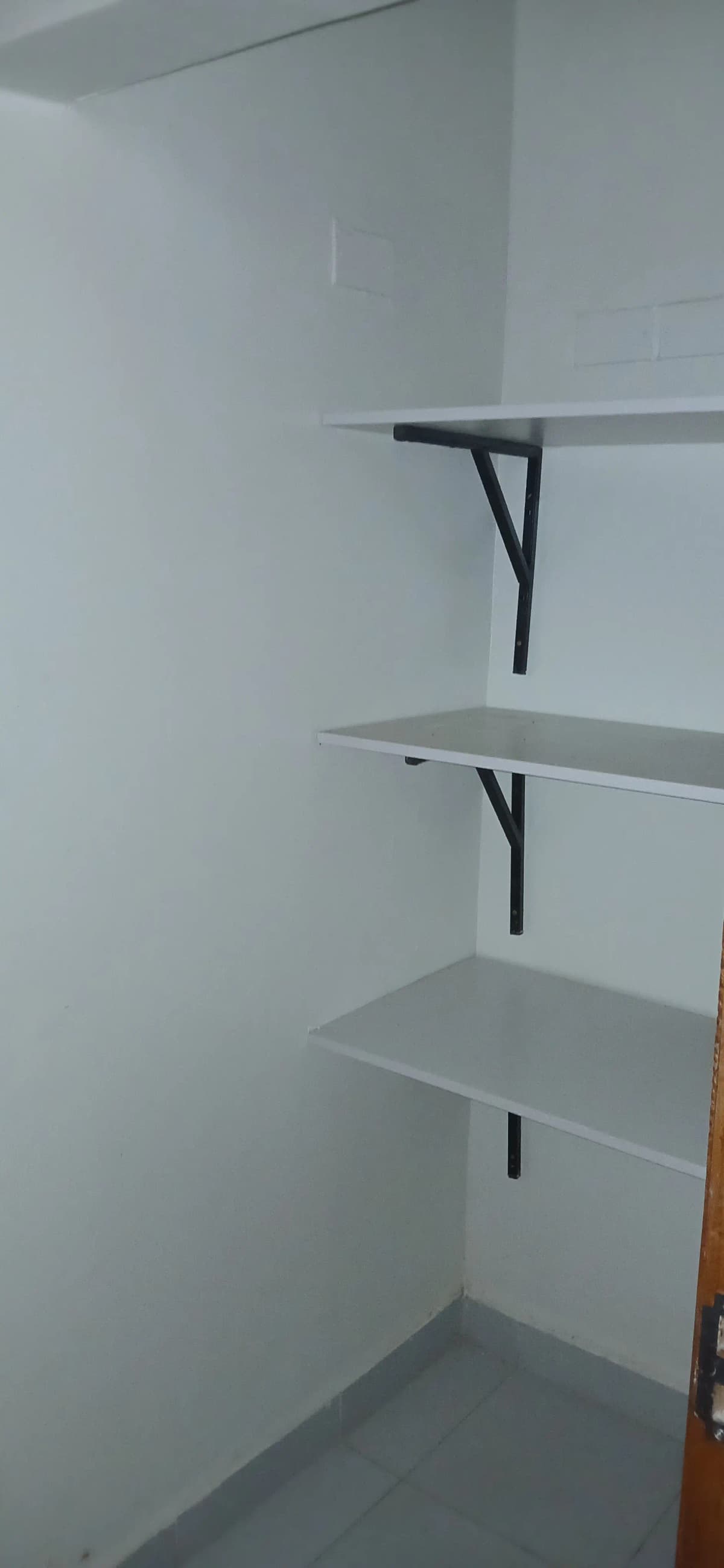 Empty shelving unit with three floating shelves, white walls