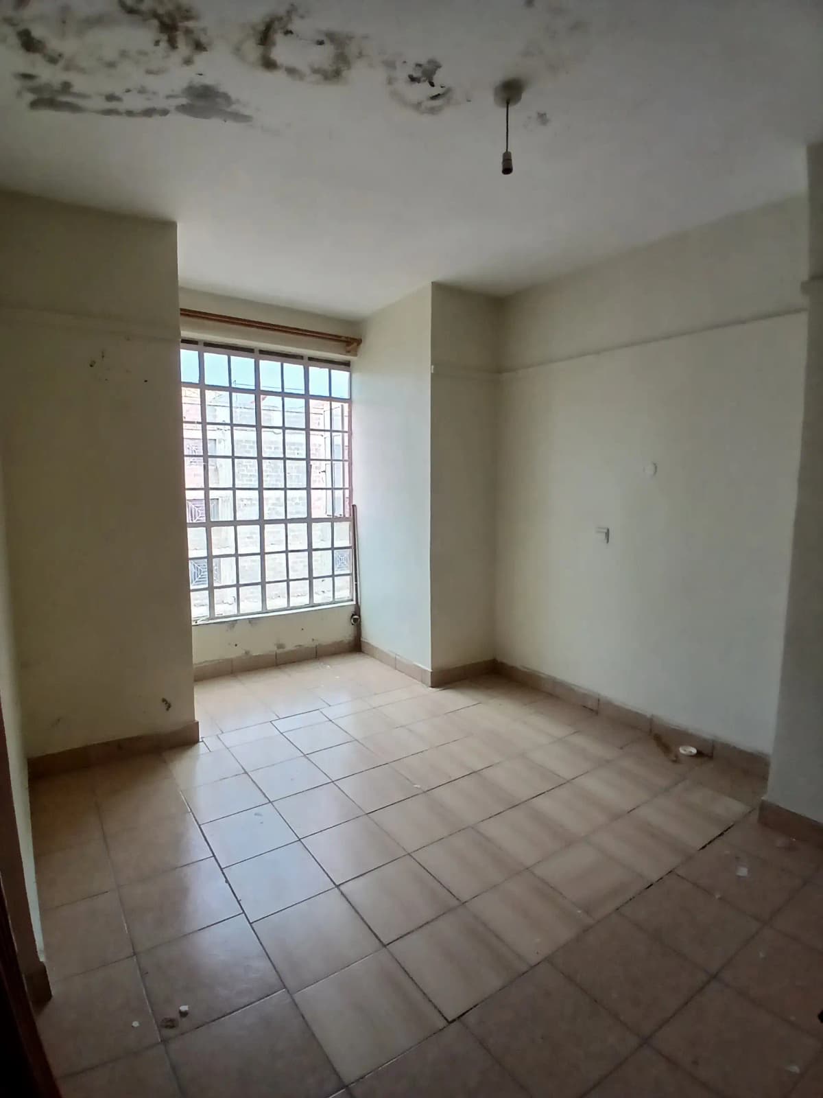 Empty living room with tiled floor and barred window