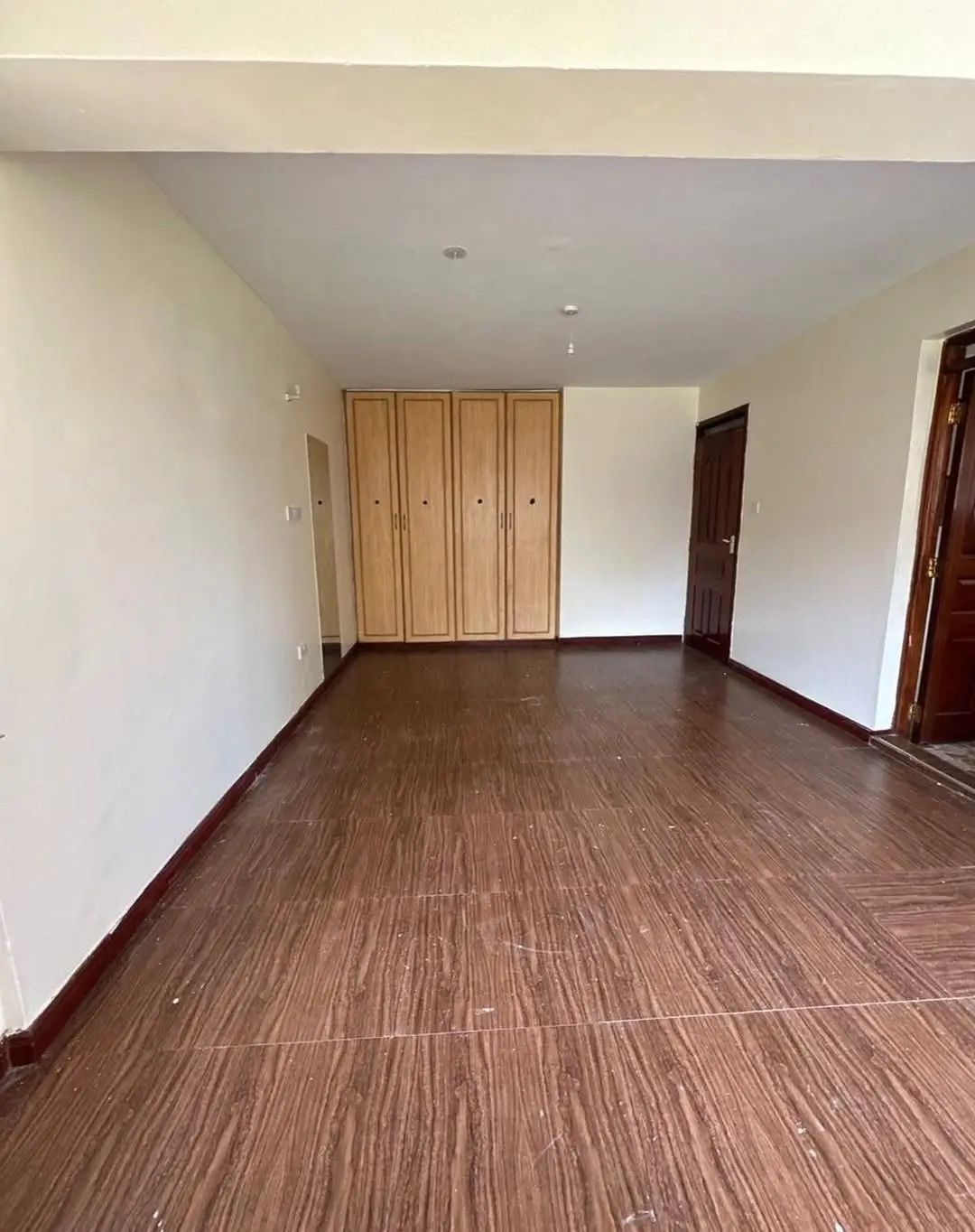 Spacious bedroom with wooden wardrobe and wood-grain flooring