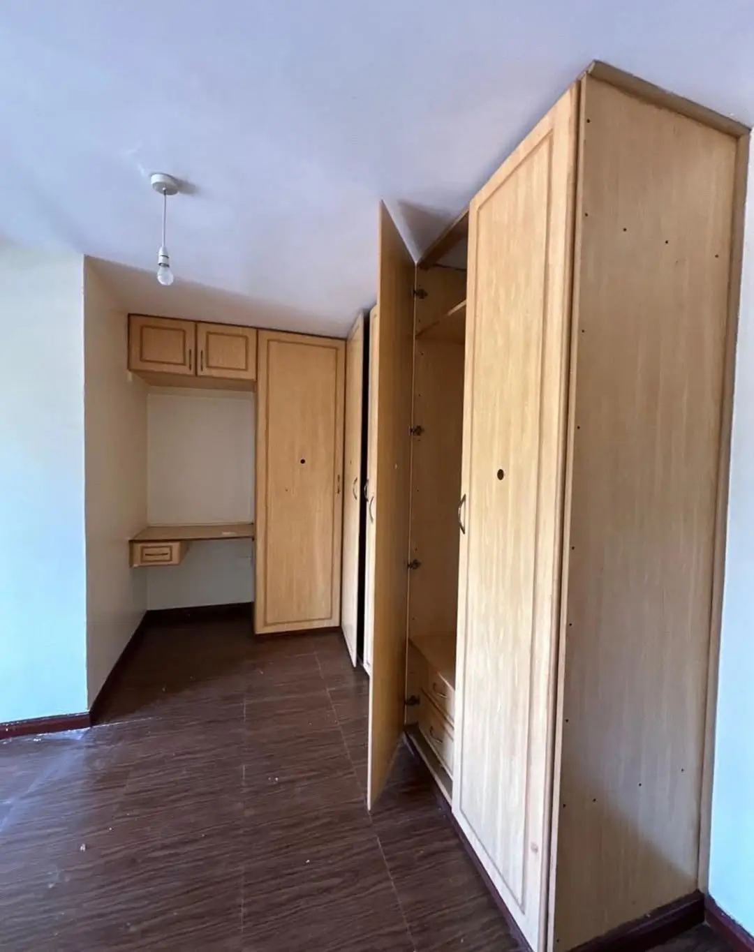 Spacious bedroom with built-in wardrobes and dark wood flooring