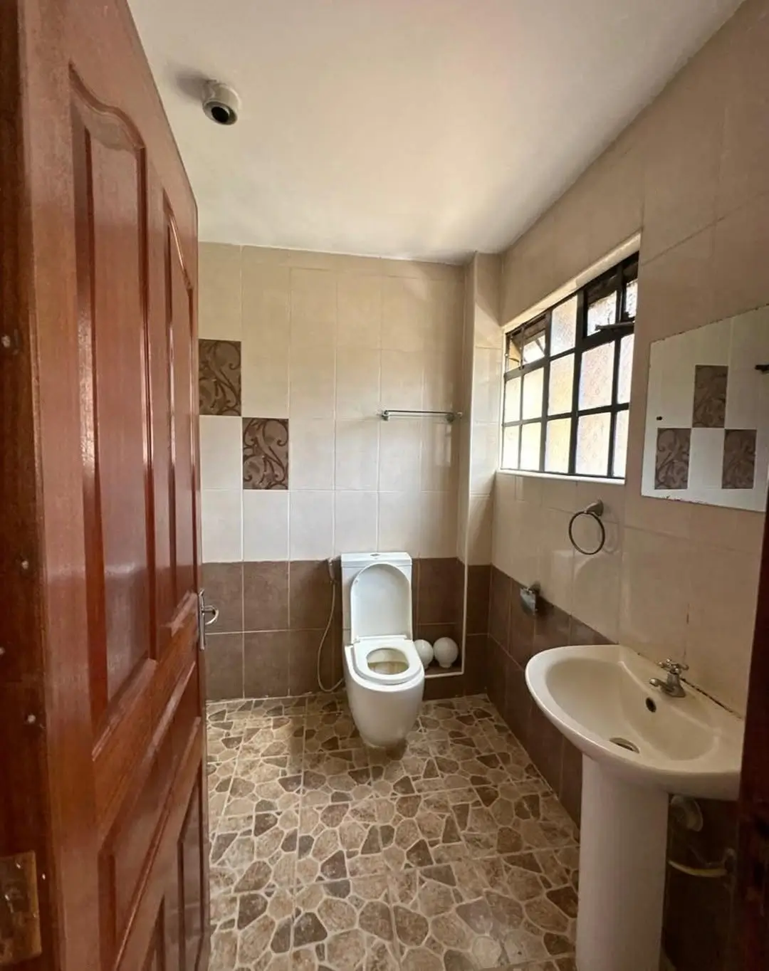 Bathroom with toilet, pedestal sink, and tiled flooring