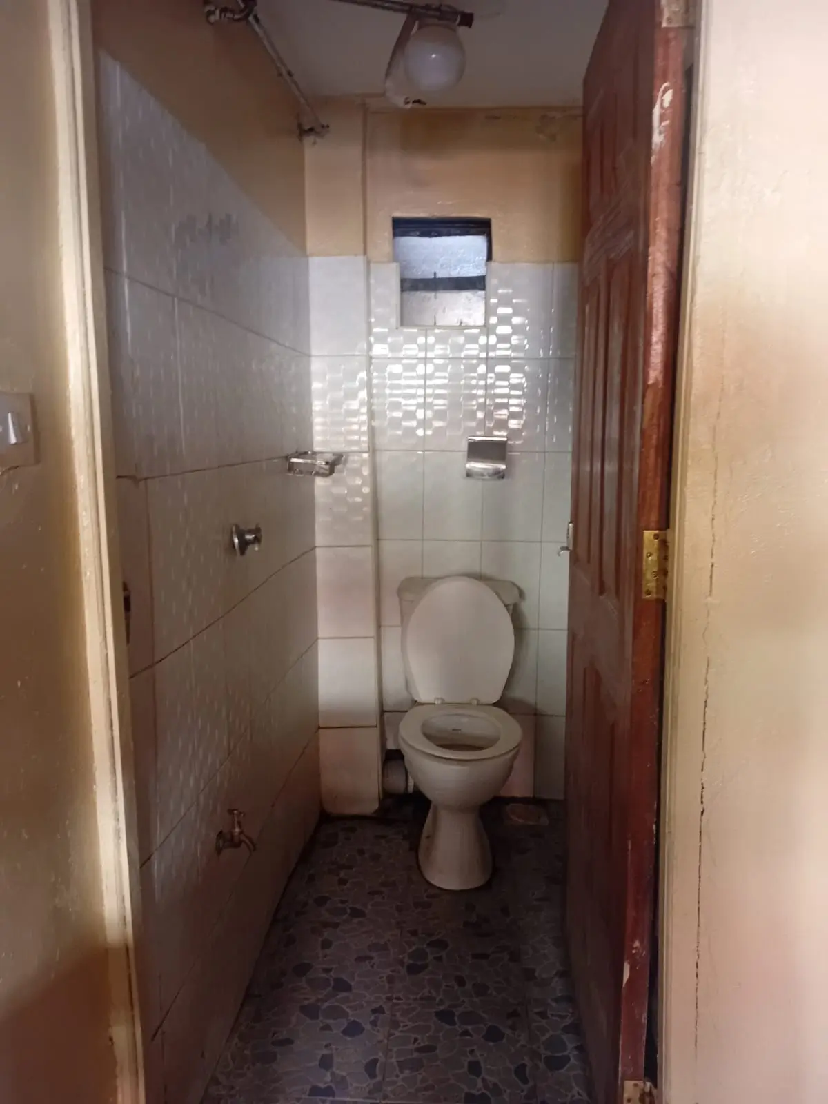 Compact bathroom with toilet, sink, and tiled shower enclosure
