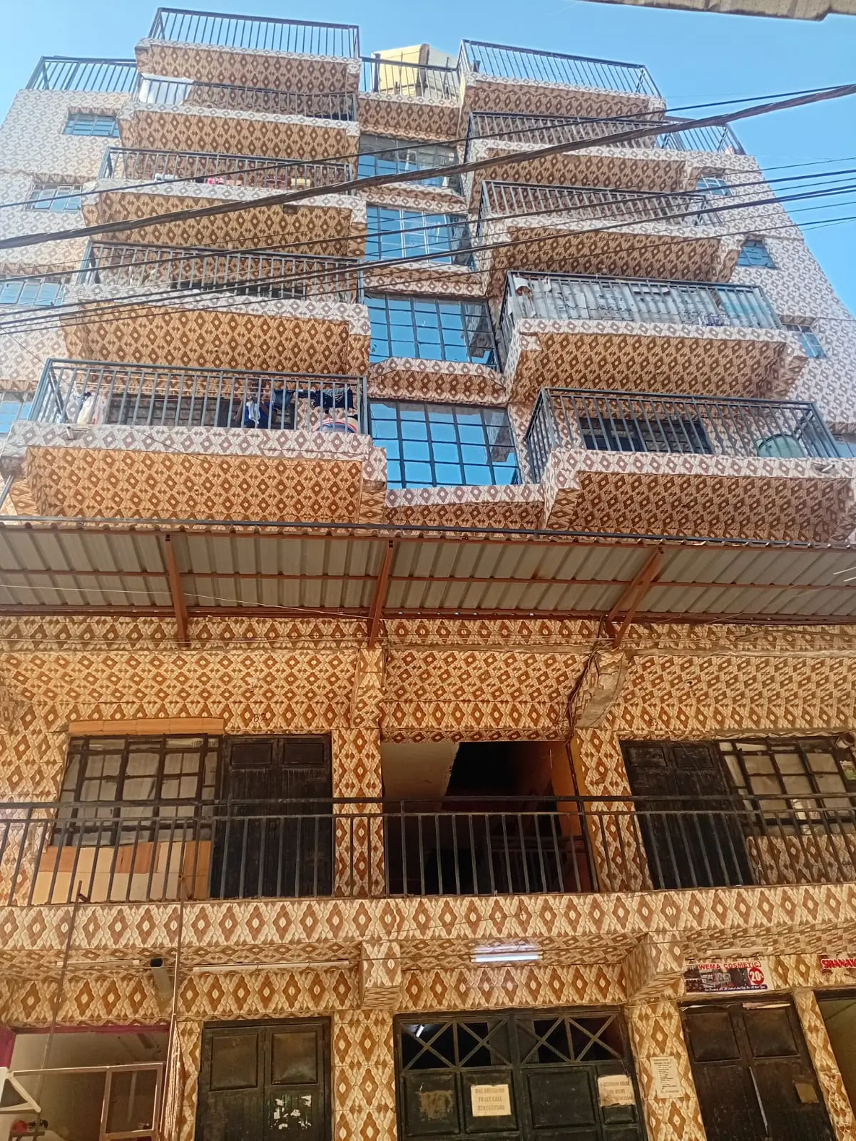Multi-story residential building facade with balconies and ground floor storefronts