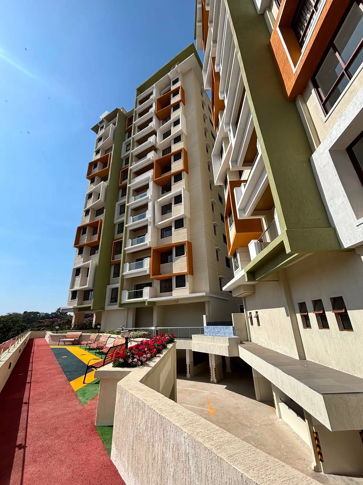 Tall multi-storey apartment block with green facade and landscaping