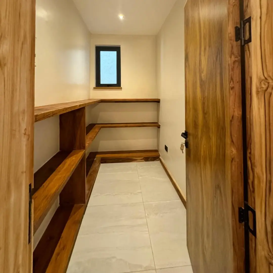 Narrow pantry with wooden shelving and small window
