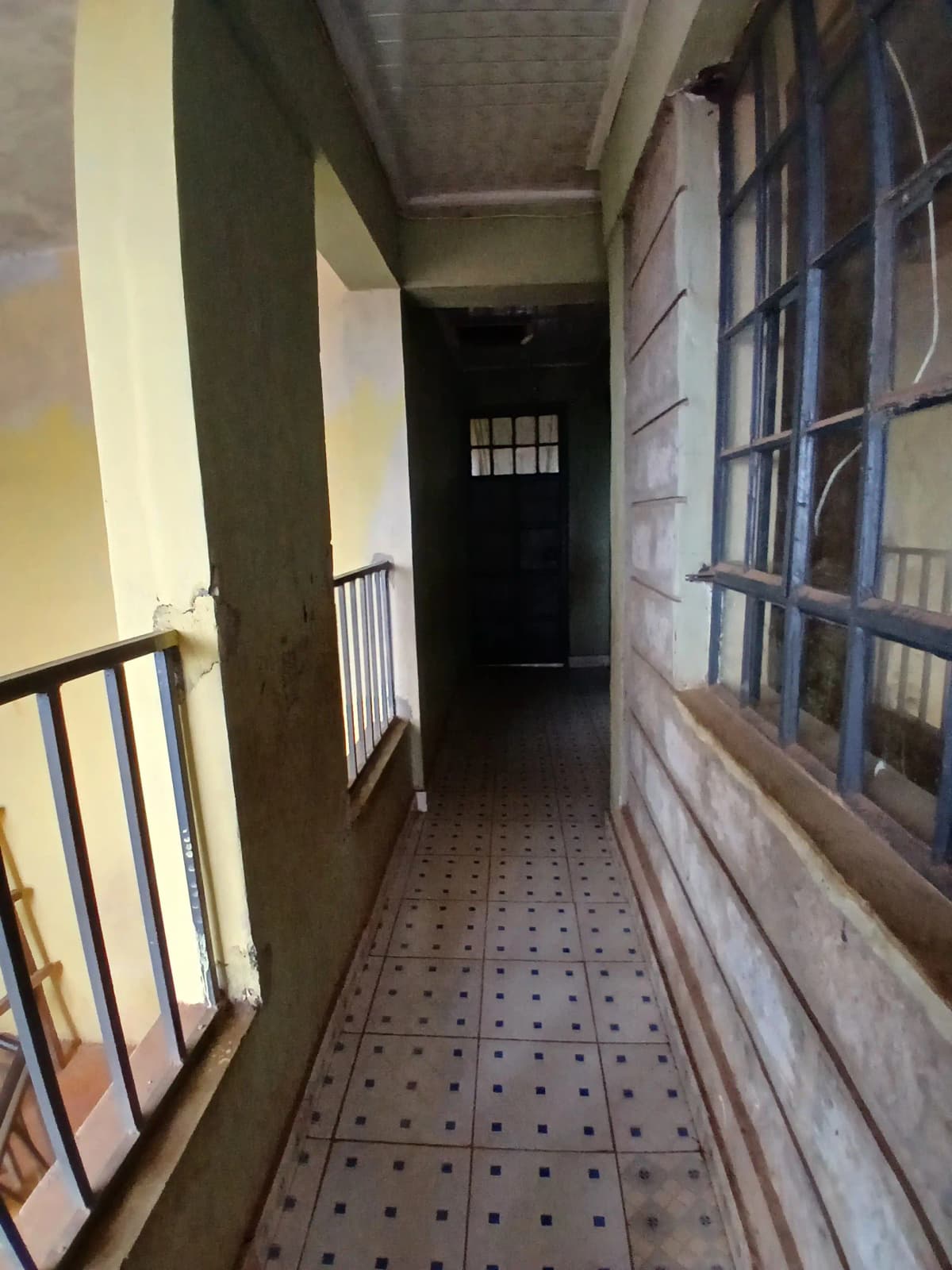 Long narrow corridor with metal railings and tiled flooring
