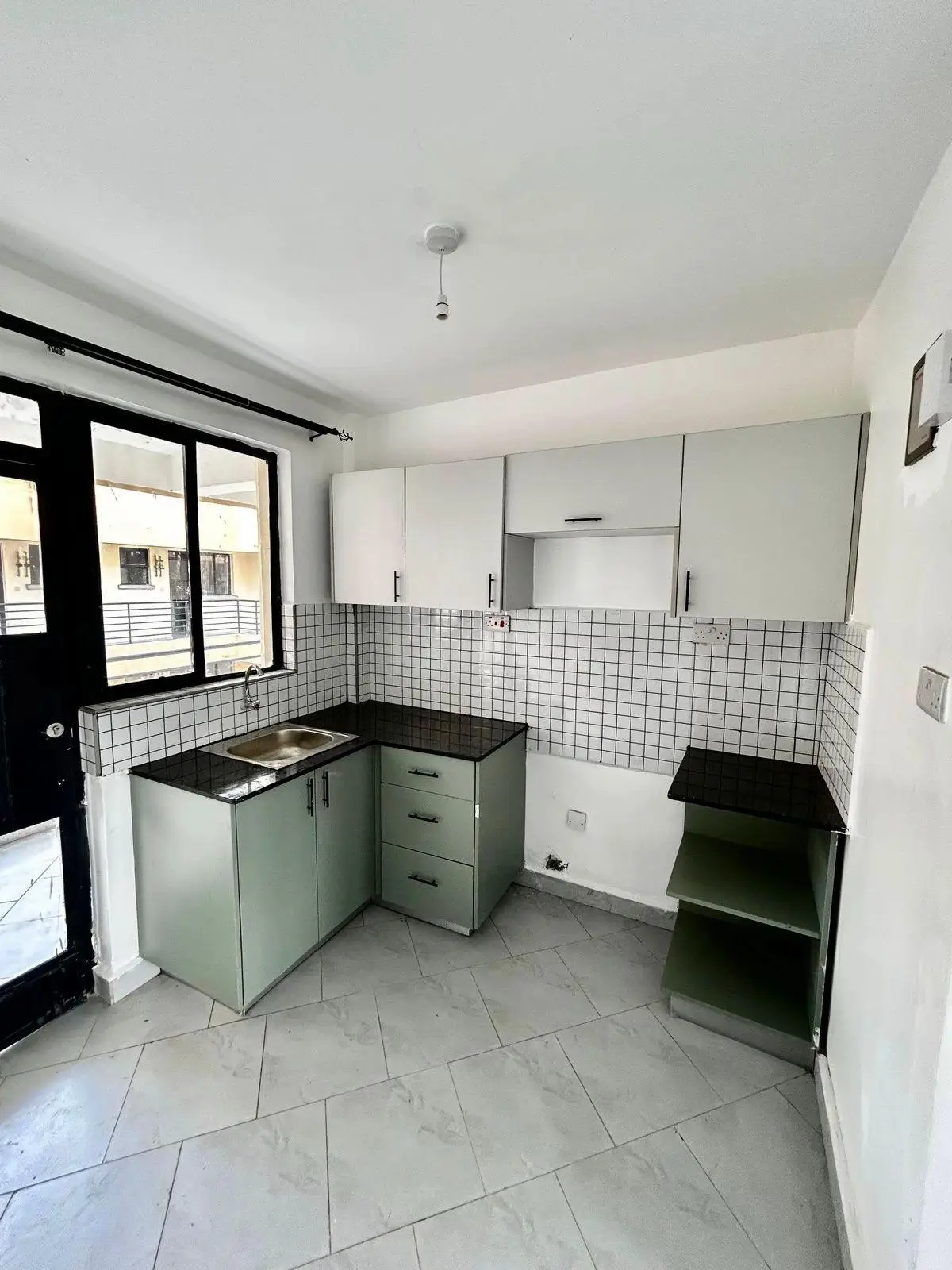 Modern kitchen with sage green cabinetry and black countertops