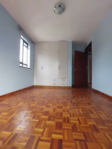 Spacious bedroom with parquet flooring and built-in wardrobes