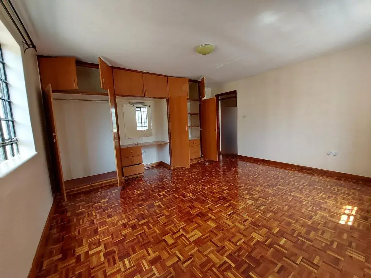 Spacious bedroom with wooden built-in wardrobes, herringbone flooring