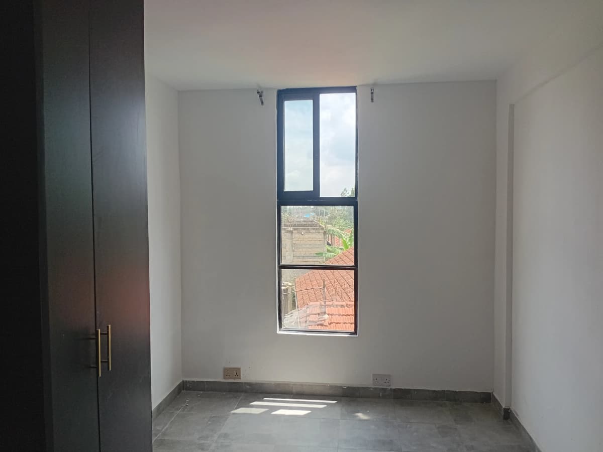 Unfurnished bedroom with tall window and built-in wardrobe