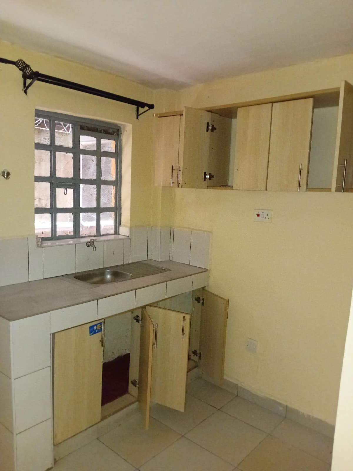 Compact yellow kitchen with sink, stove, and wall cabinets