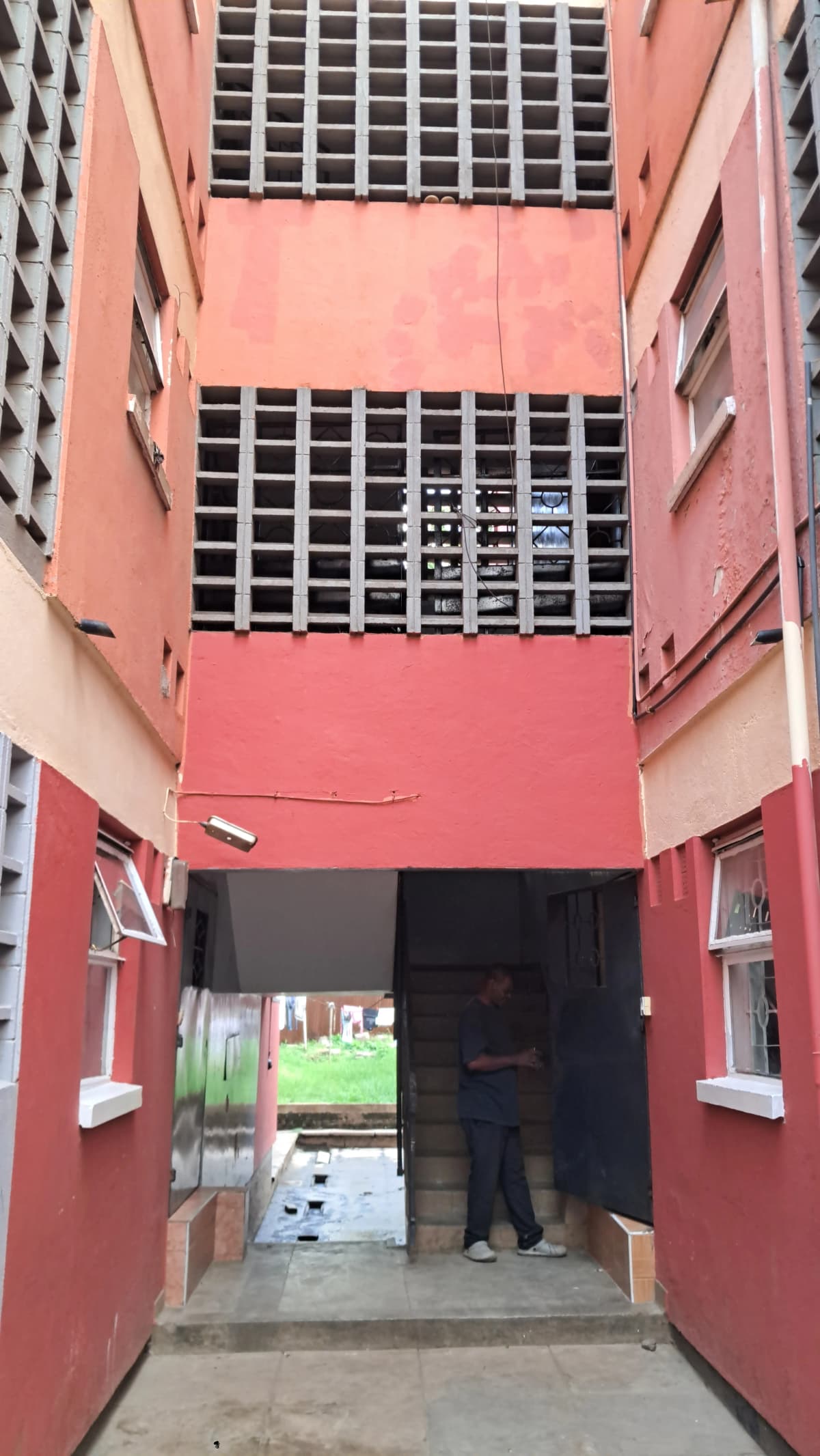 Red building entrance hallway with security gates and compound view