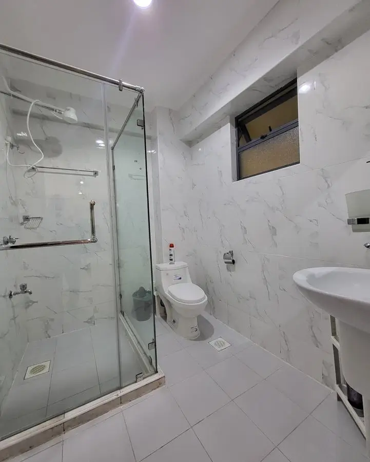 Modern bathroom with walk-in shower, toilet, and dual vanity sinks