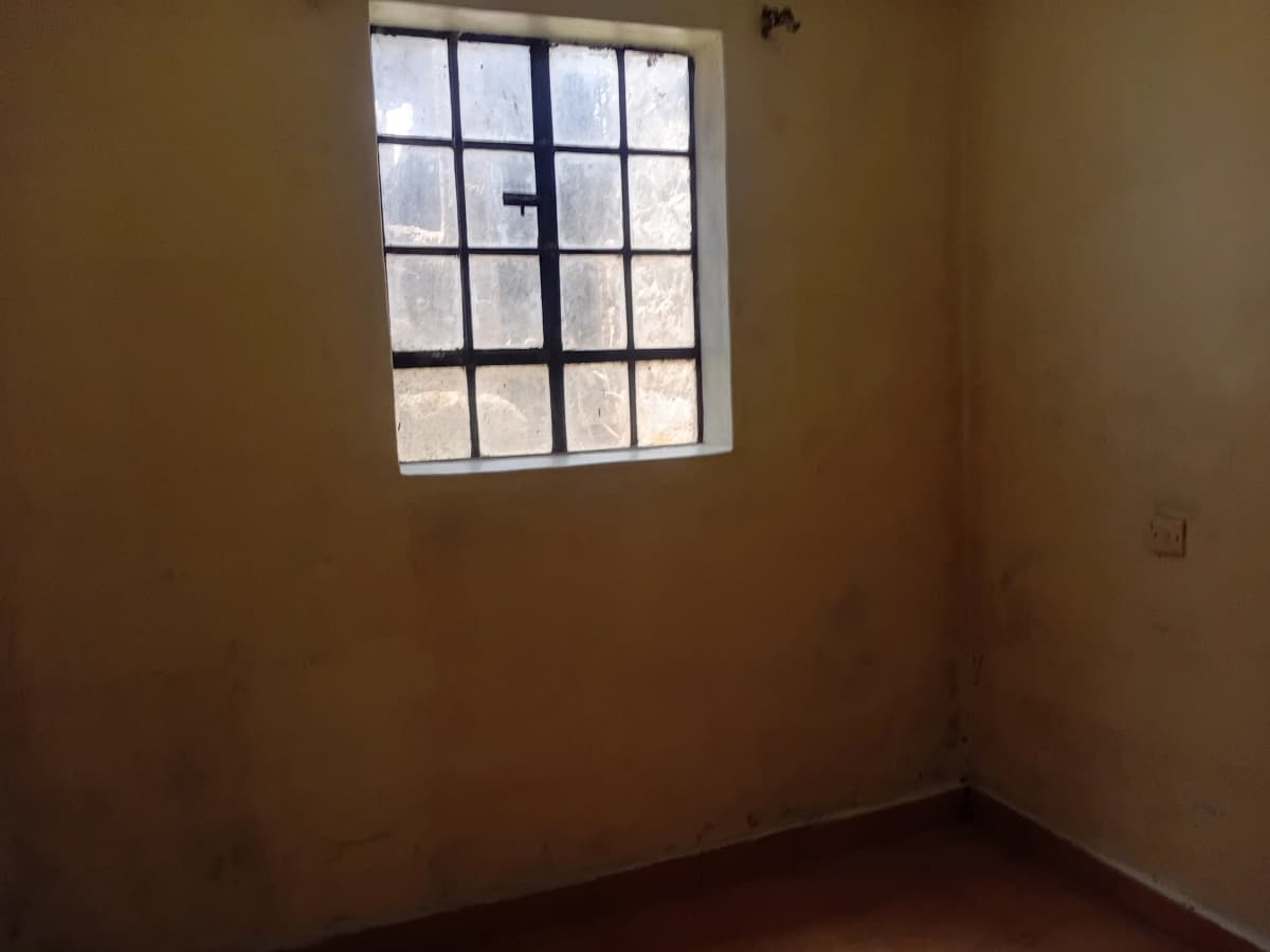 Unfurnished bedroom with barred window and terracotta walls
