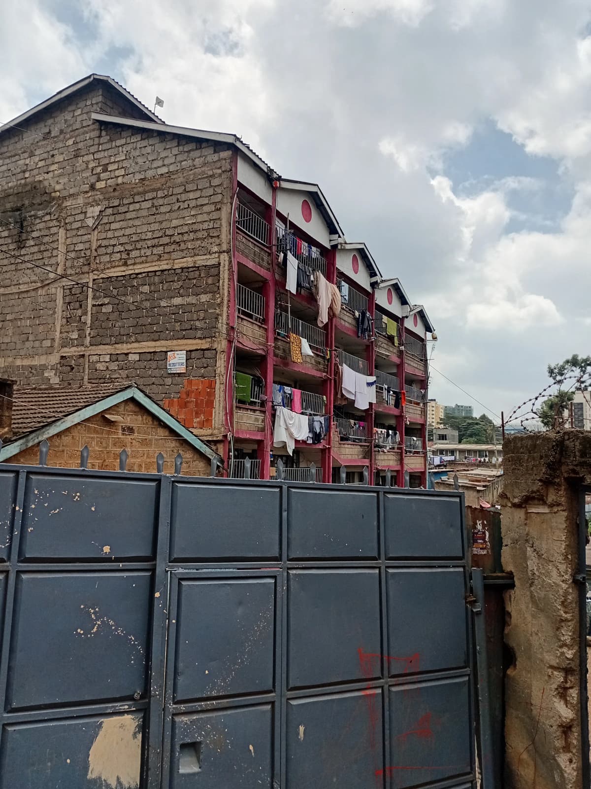 Multi-story residential building with red metal gate entrance