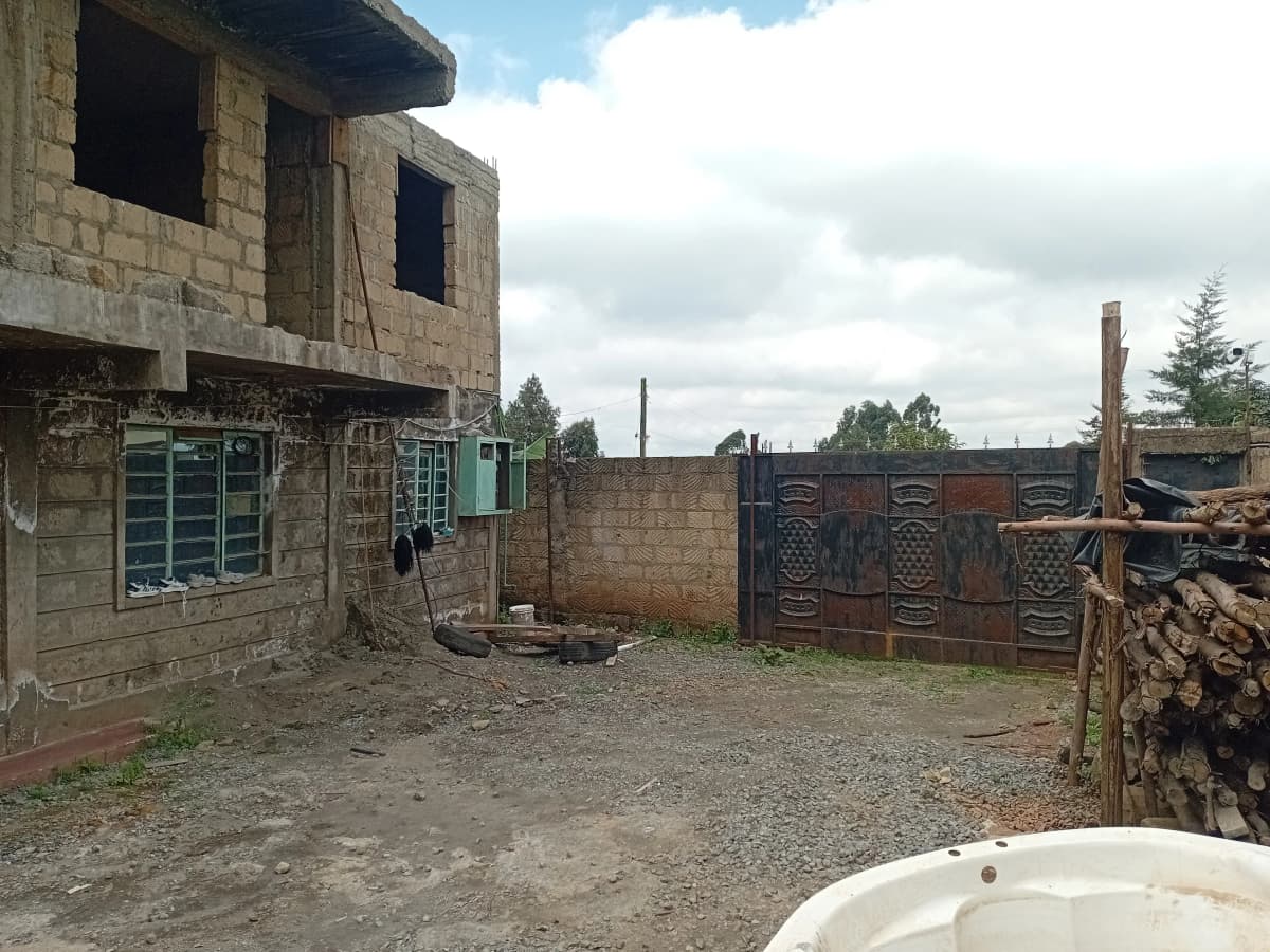 Unfinished concrete building with compound gate and grounds