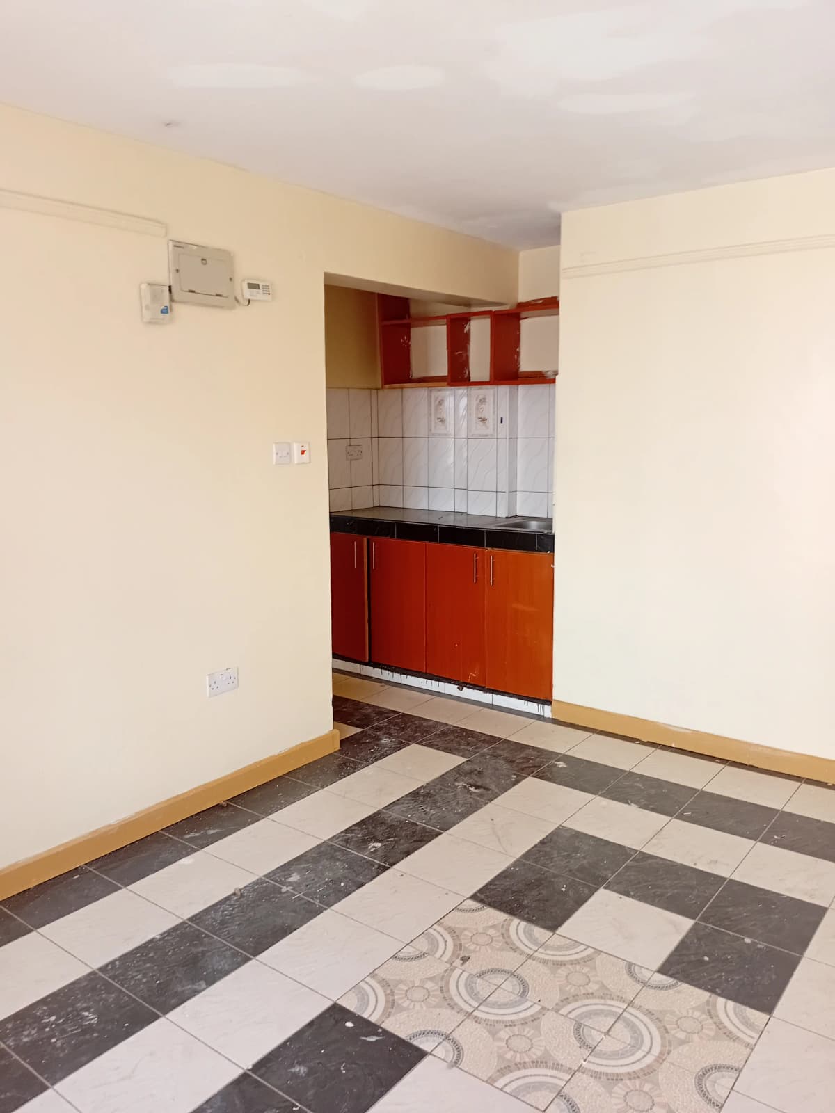 Compact kitchen with red cabinetry and black countertop