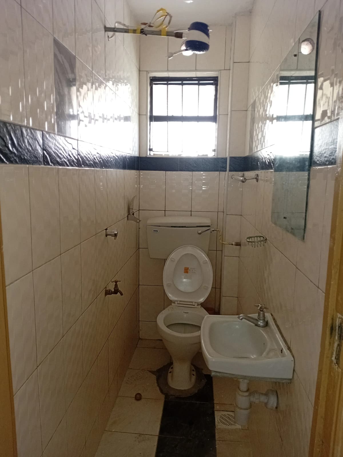 Simple bathroom with toilet, sink, and tiled walls