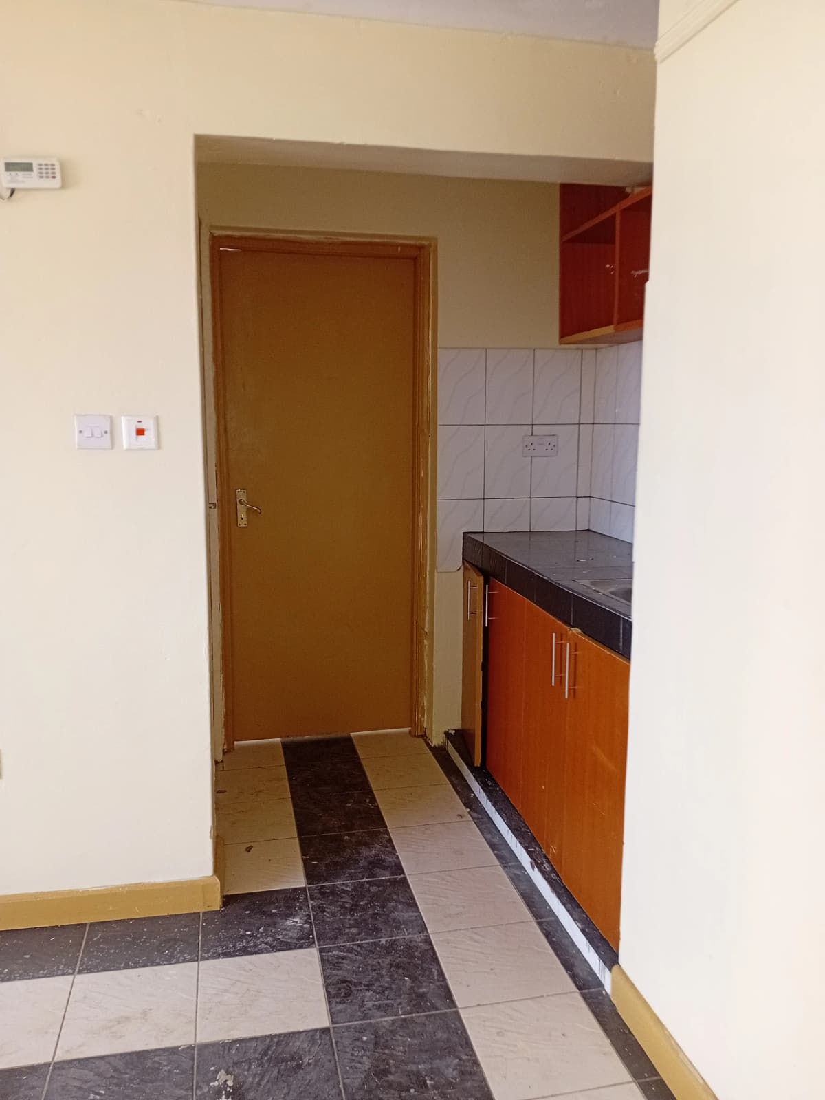 Compact kitchen with orange cabinetry and tiled flooring