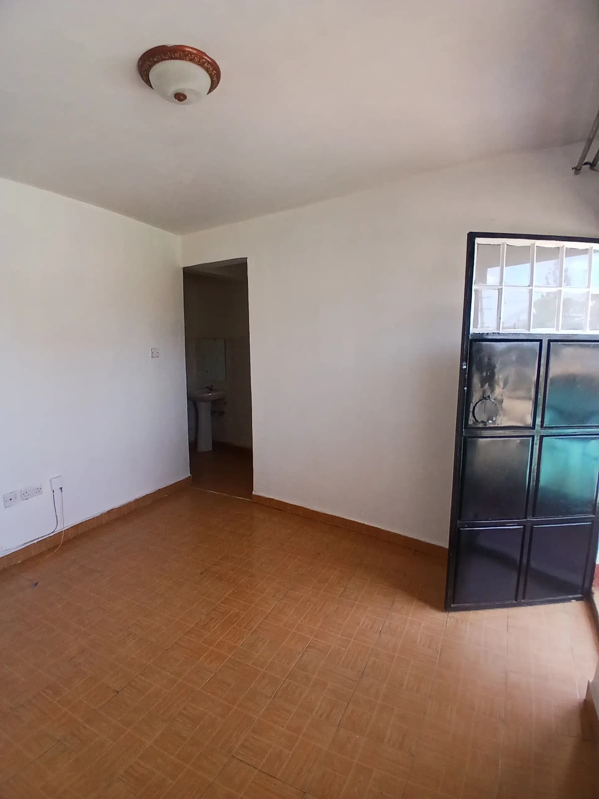 Empty living room with brown tile flooring and glass partition.