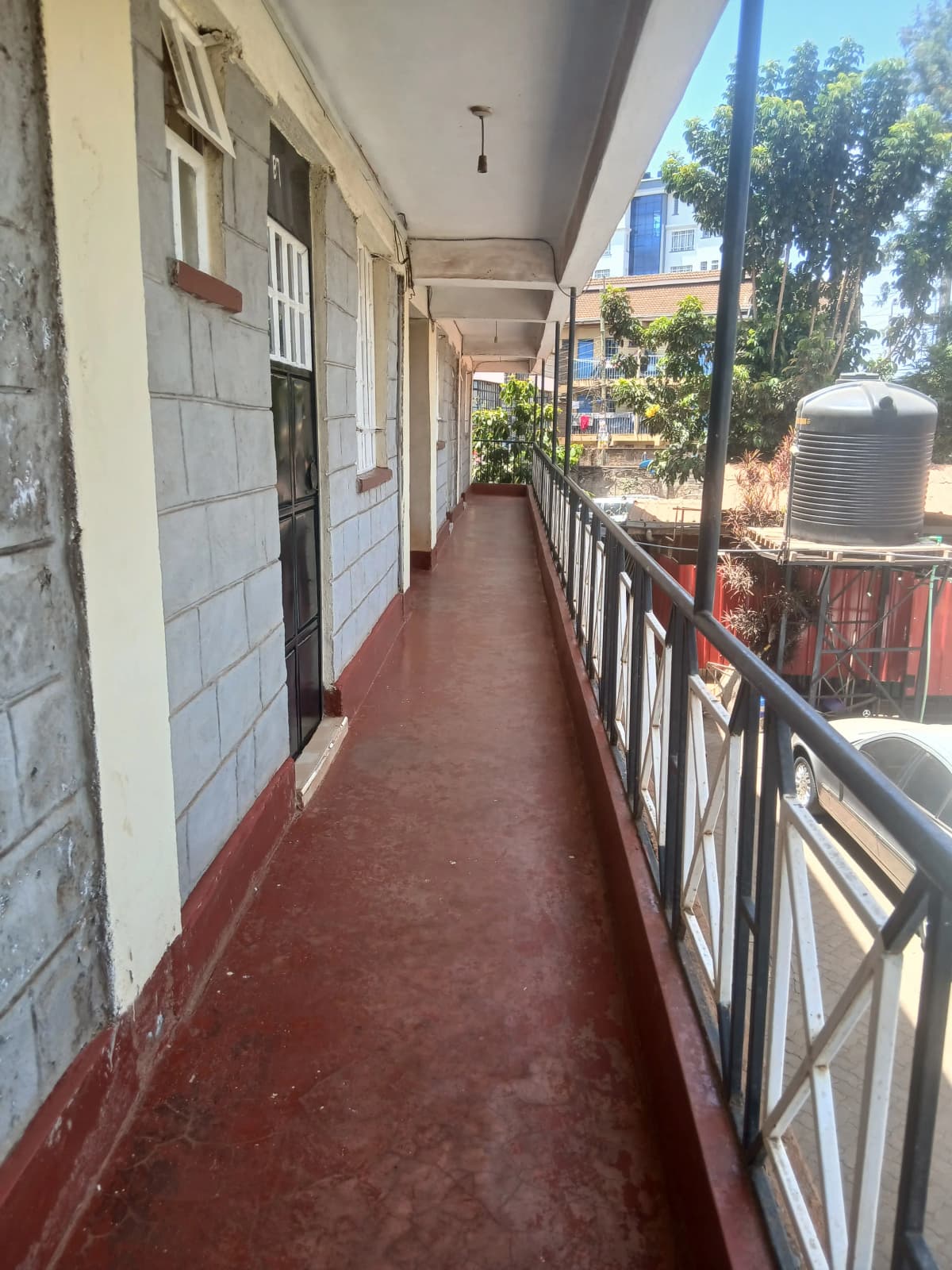 Long covered corridor with multiple unit doors and railings