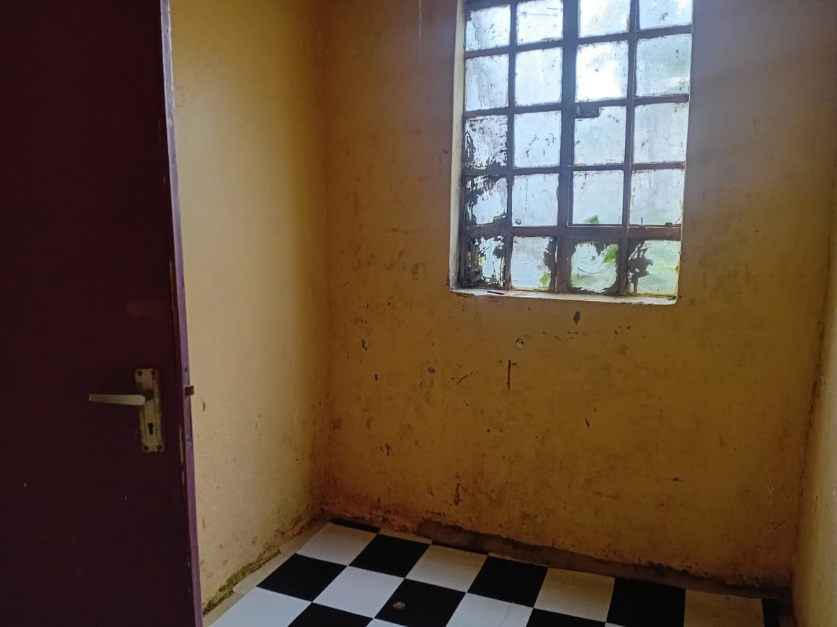 Empty bedroom with checkered floor and barred window