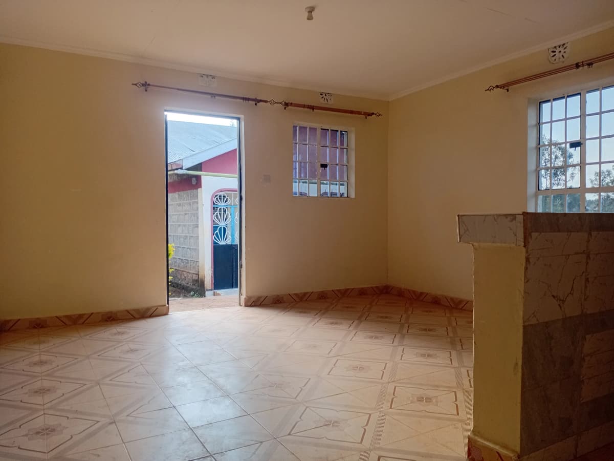Spacious empty living room with yellow walls, tiled floor