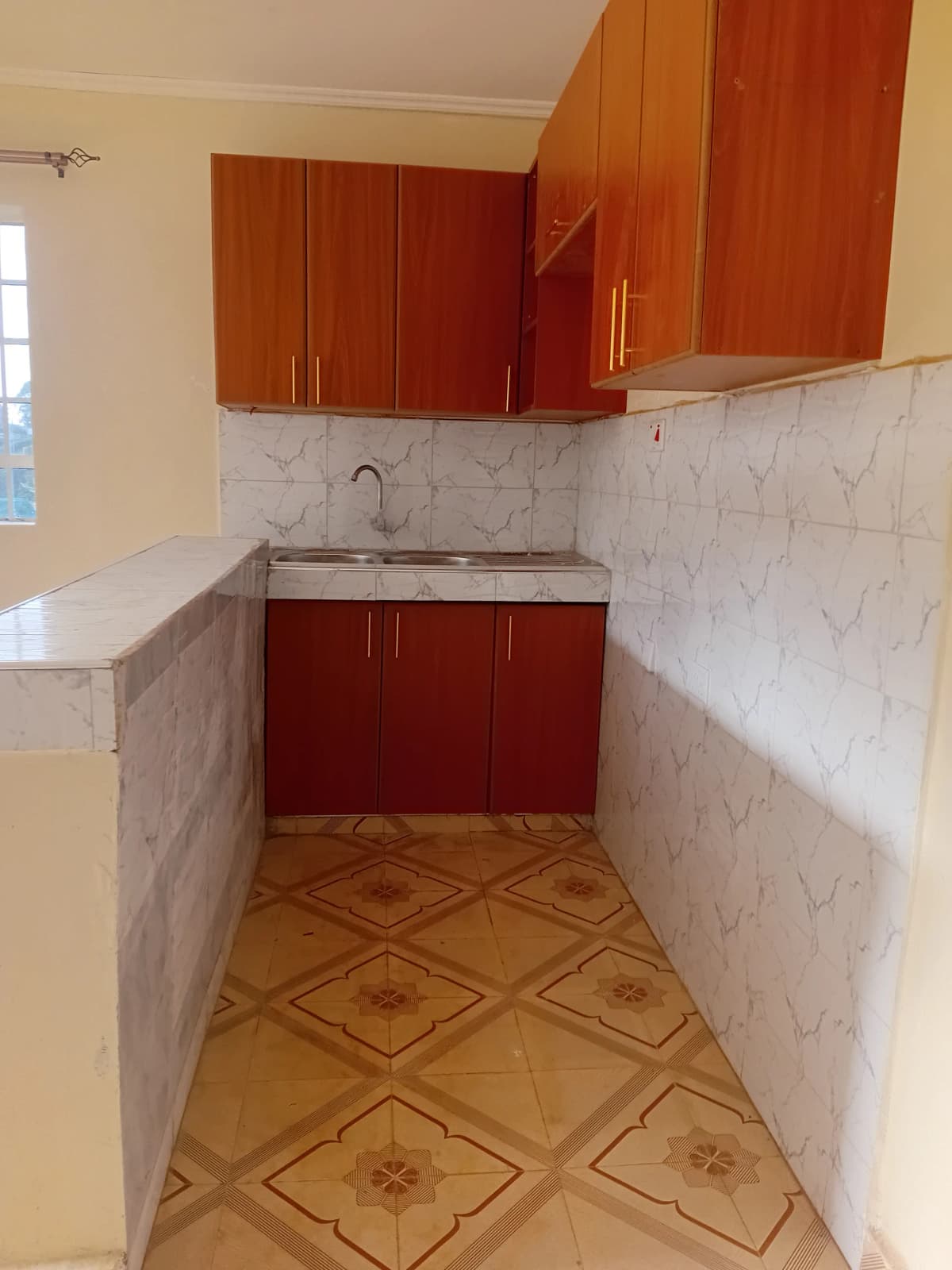 Compact kitchen with red cabinets and marble backsplash