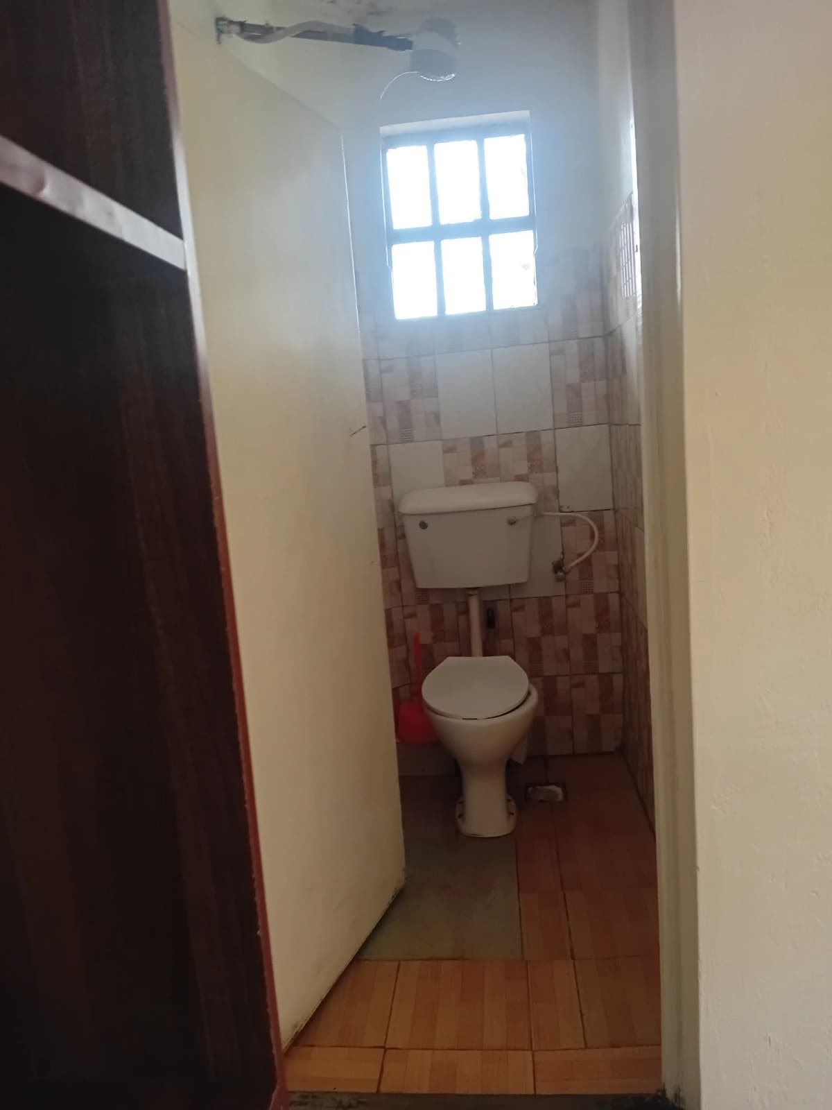 Compact bathroom with toilet, window, and terracotta flooring