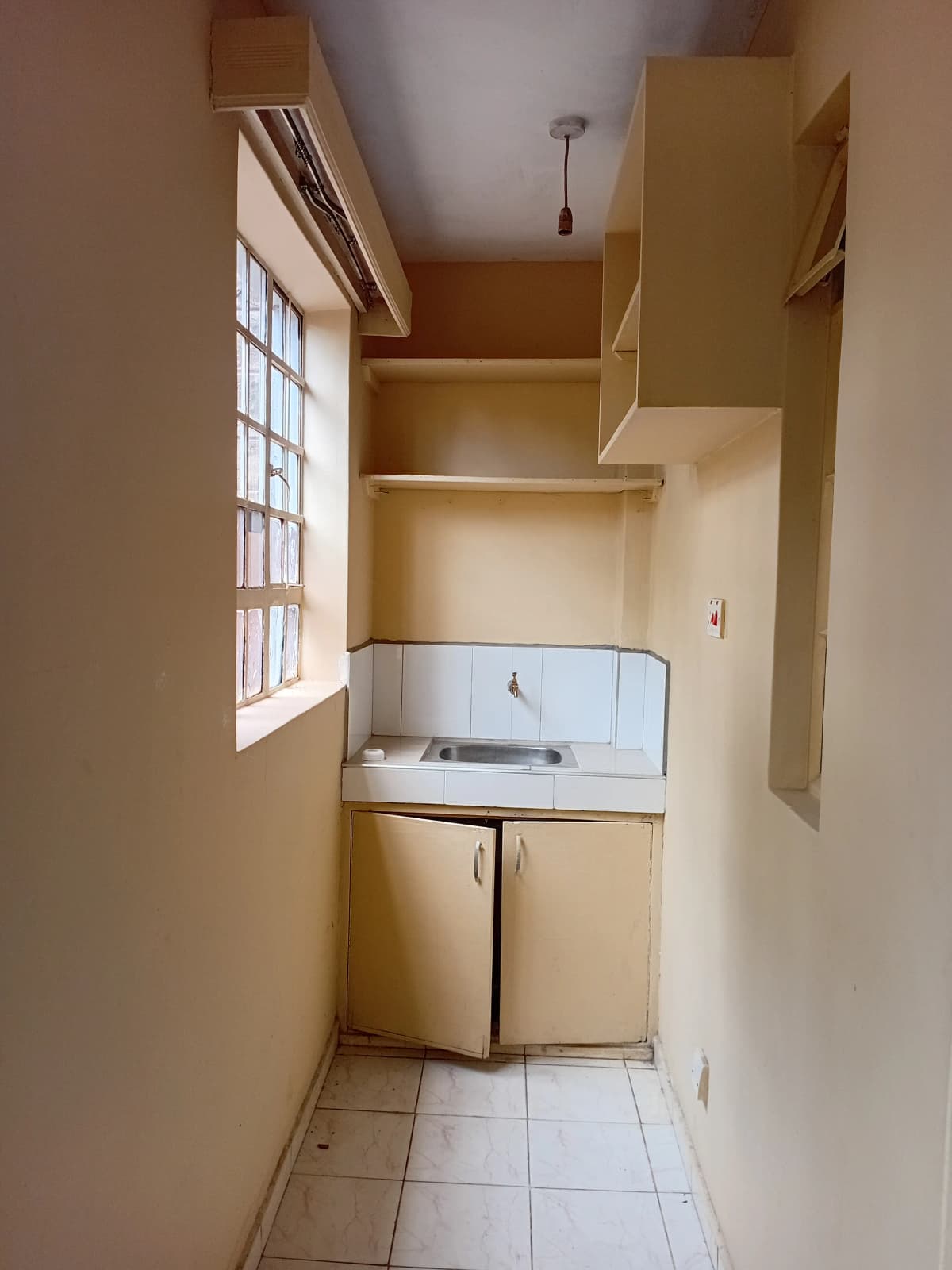 Compact kitchen with sink, stove, and upper storage shelving