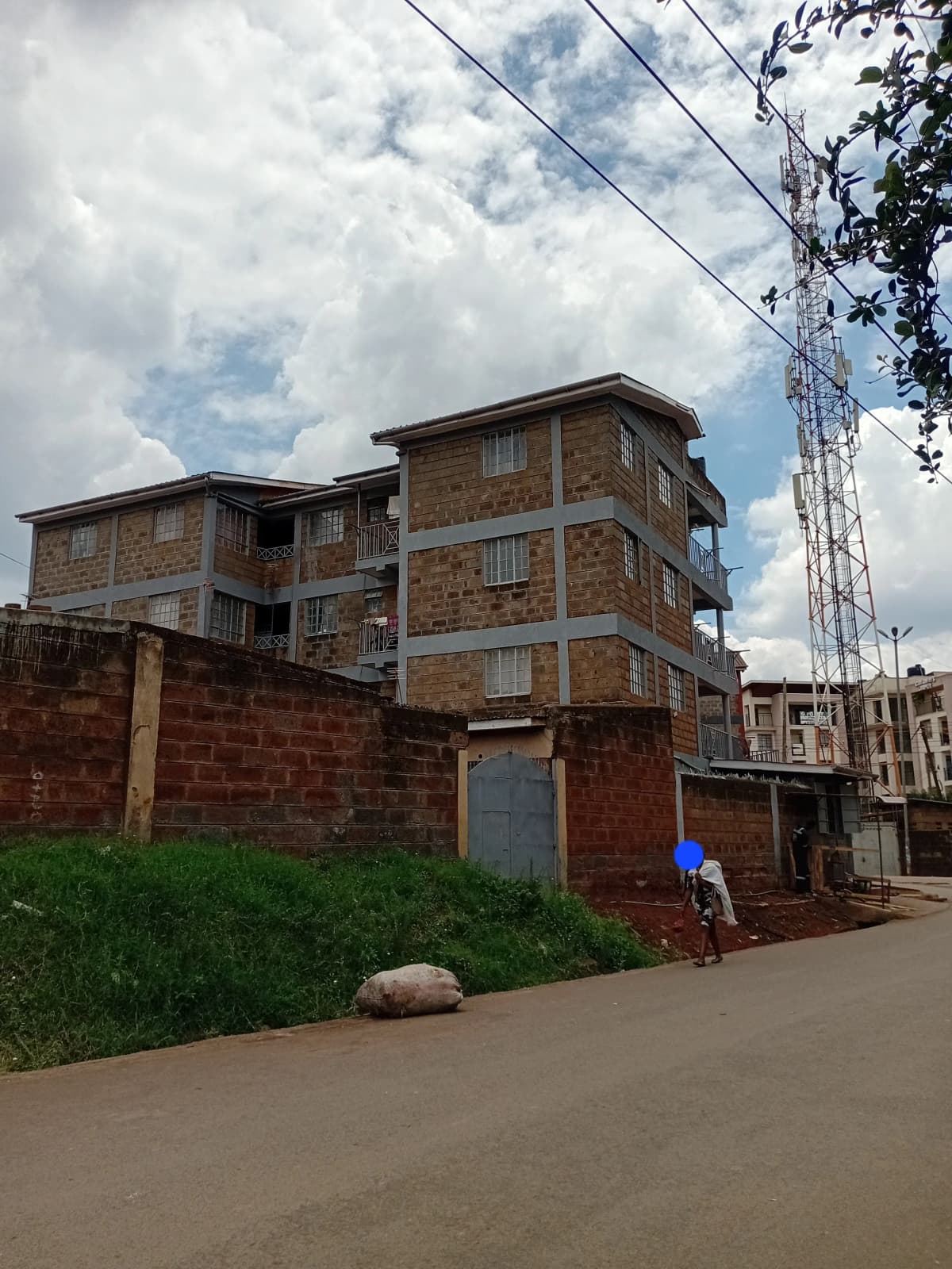 Multi-story residential building with brick facade and compound wall